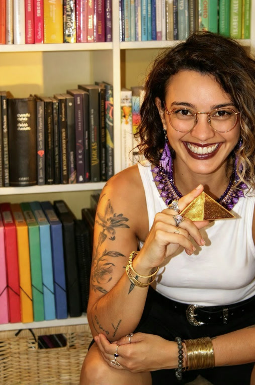 Vanesa sonríe frente a su librería sosteniendo una pequeña pirámide dorada
